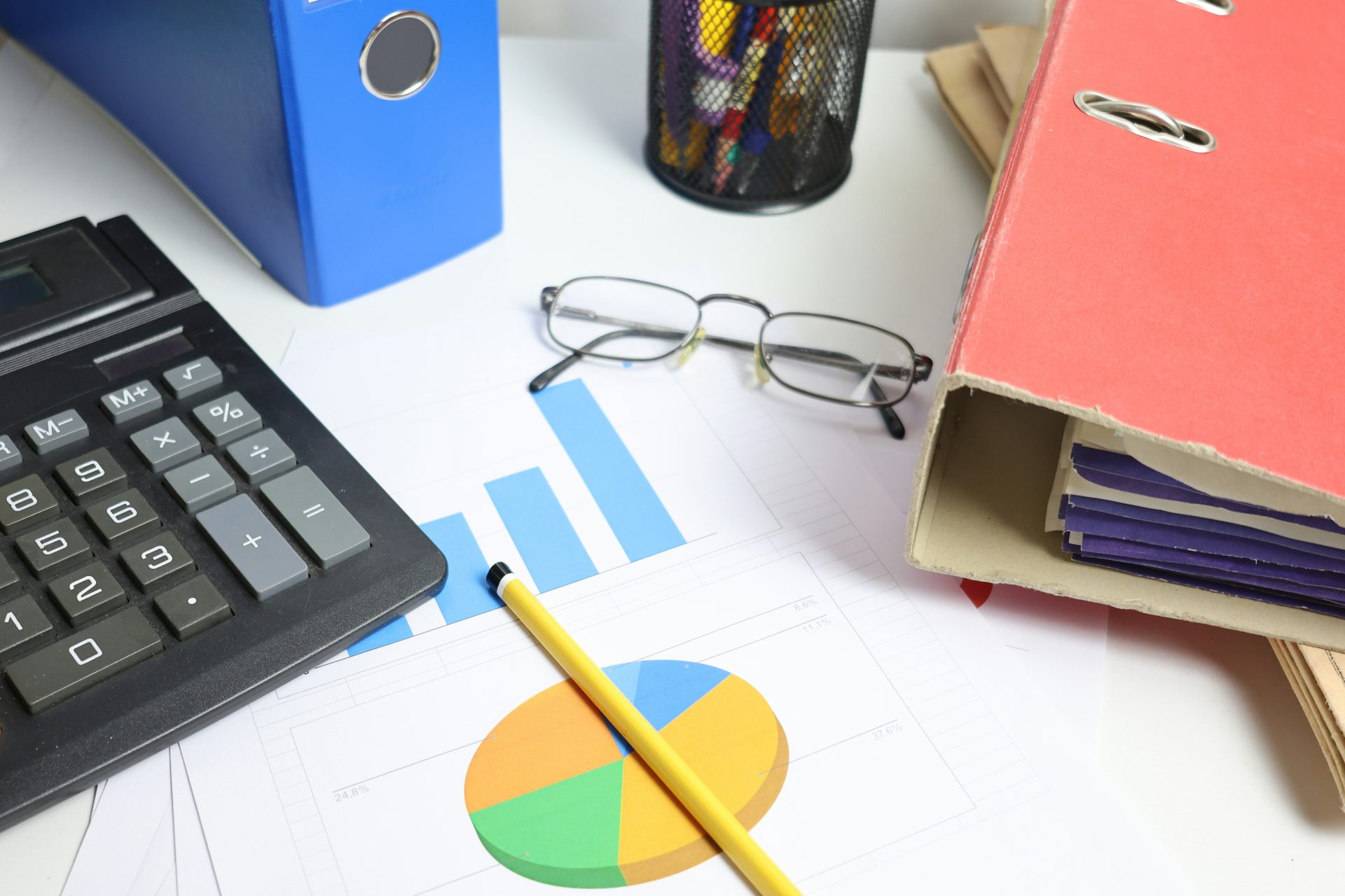 Schreibtisch mit Taschenrechner, Diagrammen und Ordnern